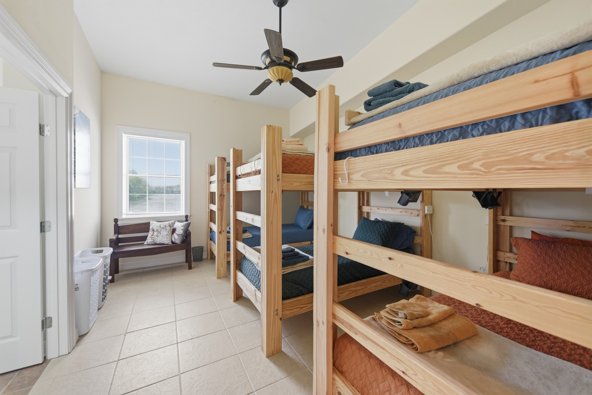 5255 Ganske Road Burton, TX 77835 - Photo 22 of 46 One of 4 room features multiple wooden bunk beds, ideal for accommodating guests or a large groups. Rooms have ceiling fans, tile flooring, and ample natural light from a large window. Perfect for maximizing sleeping space.