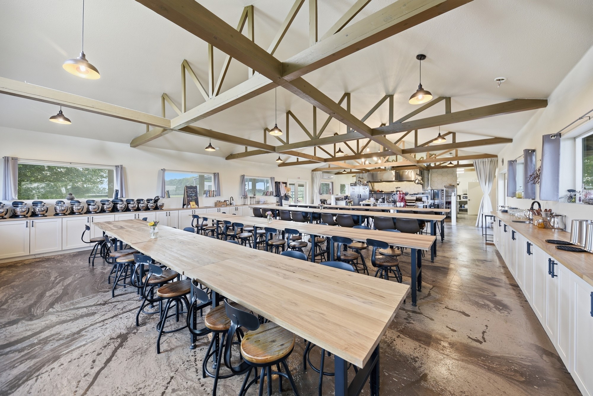 5255 Ganske Road Burton, TX 77835 - Photo 29 of 46 Dining features high ceilings with exposed beams, ample natural light from large windows, and extensive counter space with seating. It's perfect for hosting and culinary activities, blending rustic charm with modern functionality.