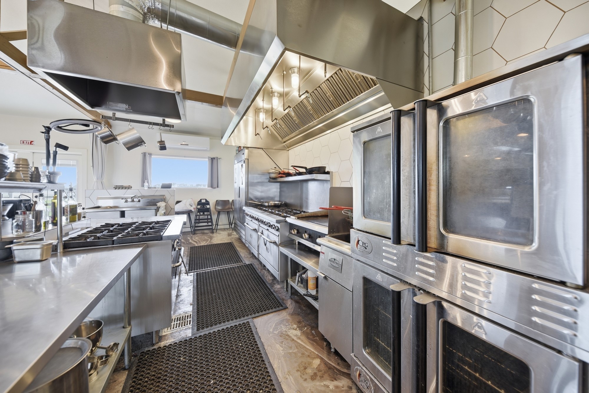 5255 Ganske Road Burton, TX 77835 - Photo 31 of 46 Stainless steel appliances, including multiple ovens and stovetops. The space features ample counter space, industrial ventilation, and a bright, airy atmosphere with plenty of natural light. Ideal for culinary enthusiasts or catering purposes.