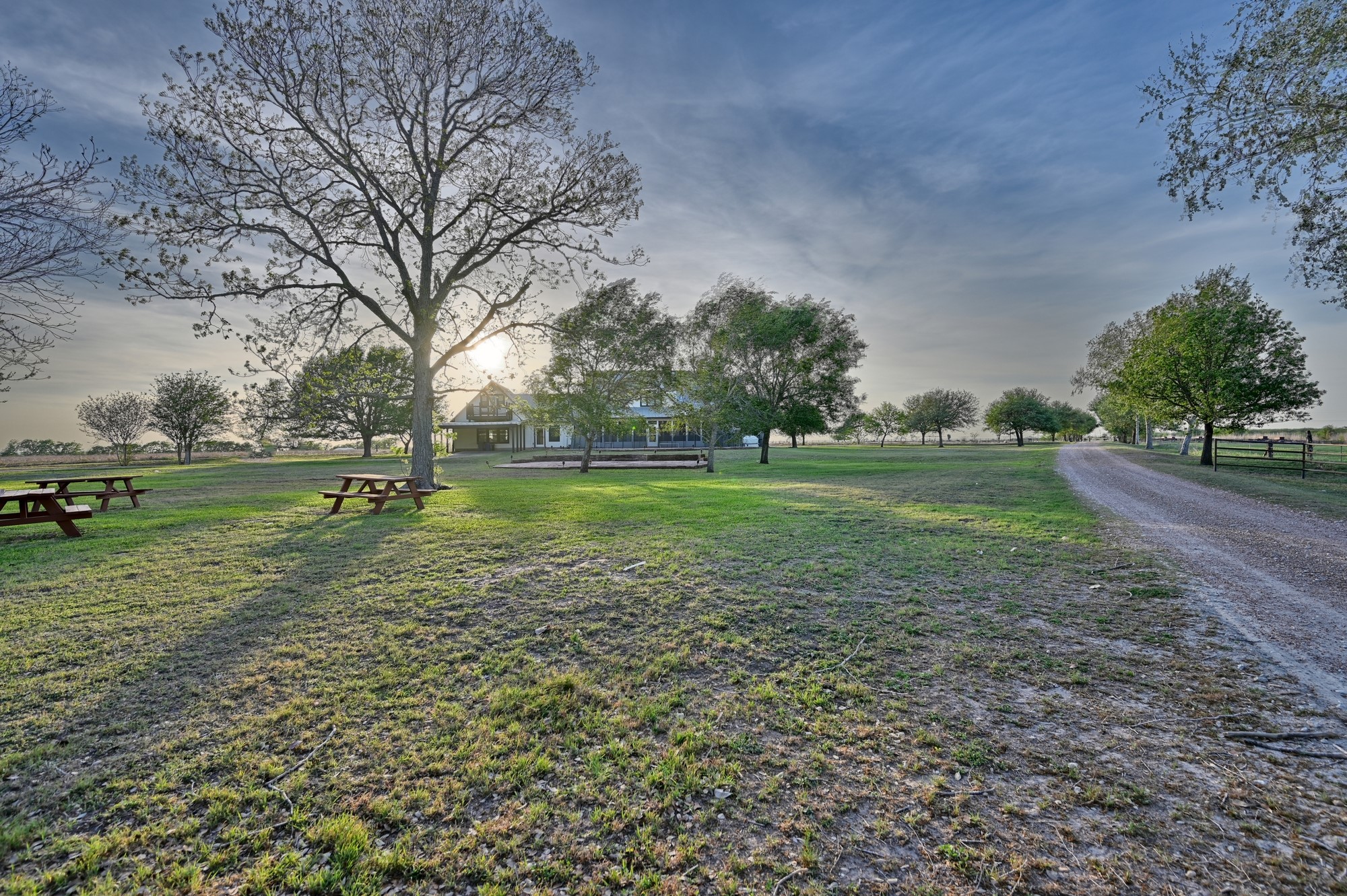 5255 Ganske Road Burton, TX 77835 - Photo 40 of 46 This serene property features a spacious yard with mature trees, picnic tables, and a gravel driveway leading to a charming house. It's perfect for enjoying outdoor activities and peaceful country living.