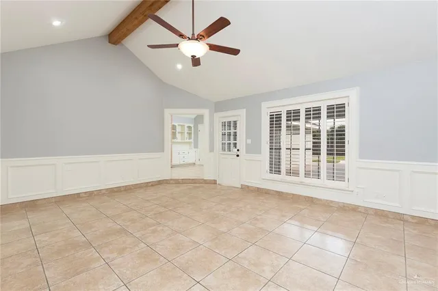 an empty room with chandelier fan and window