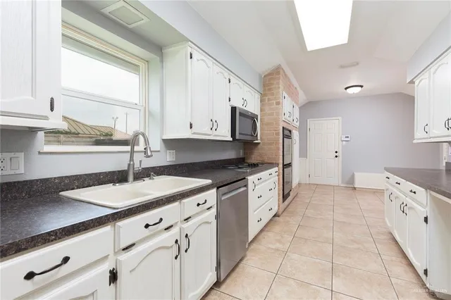 a large kitchen with granite countertop a sink dishwasher a stove and a refrigerator