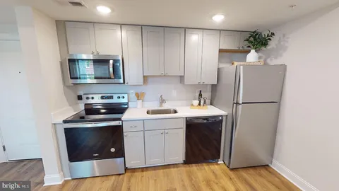 a kitchen with a sink a refrigerator and a stove top oven