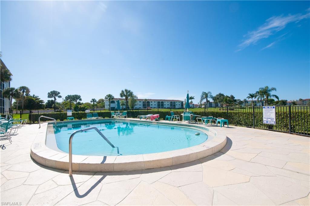37 High Point Circle East, Unit 210 Naples, FL 34103 - Photo 26 of 29 a view of swimming pool that has lawn chairs with wooden fence