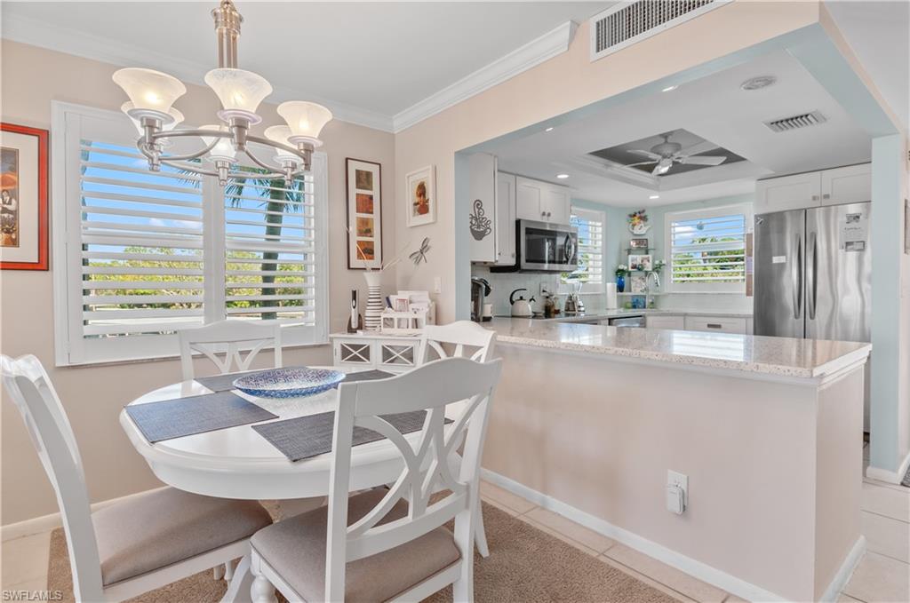 37 High Point Circle East, Unit 210 Naples, FL 34103 - Photo 4 of 29 a kitchen with stainless steel appliances granite countertop a stove top oven a sink dishwasher a dining table and chairs with wooden floor