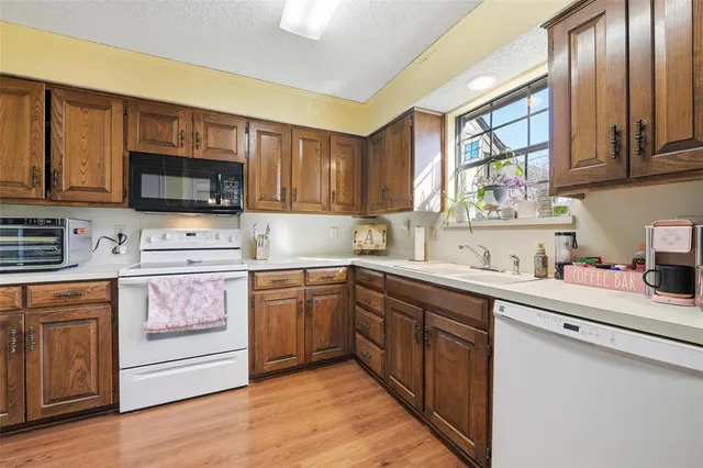 a kitchen with stainless steel appliances granite countertop a stove top oven a sink dishwasher and a microwave oven with wooden floor