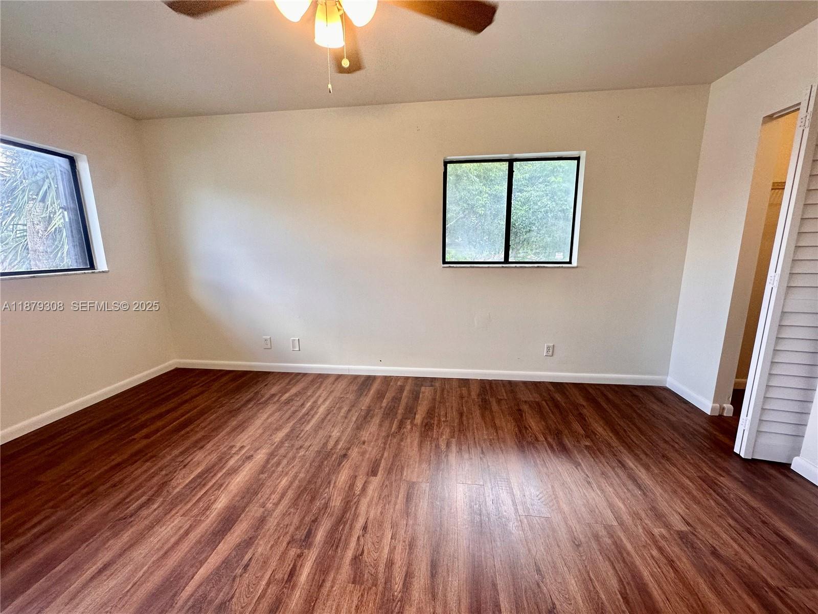 19700 Southwest 103rd Court, Unit 201 Cutler Bay, FL 33157 - Photo 11 of 21 an empty room with wooden floor chandelier fan and windows