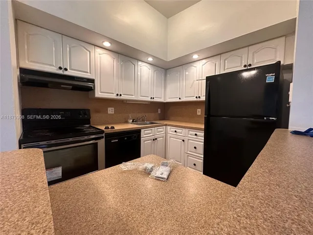 a kitchen with stainless steel appliances granite countertop a refrigerator a stove a sink and a microwave