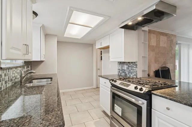 a kitchen with granite countertop a stove sink and cabinets