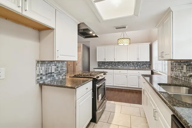 a kitchen with kitchen island granite countertop a sink and a stove