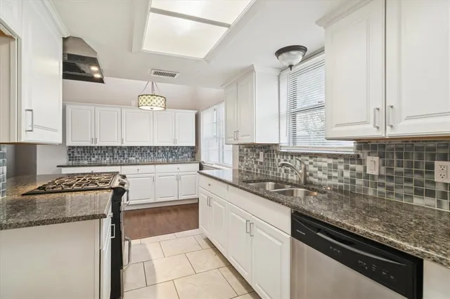 a kitchen with granite countertop a sink stainless steel appliances and cabinets