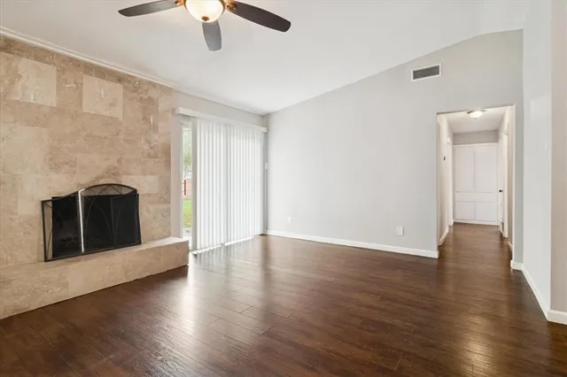 an empty room with wooden floor fireplace and windows