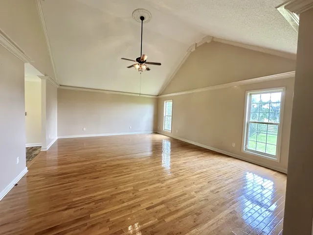 a view of empty room with wooden floor and fan