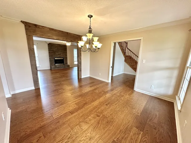 a view of a hallway with wooden floor and a chandelier