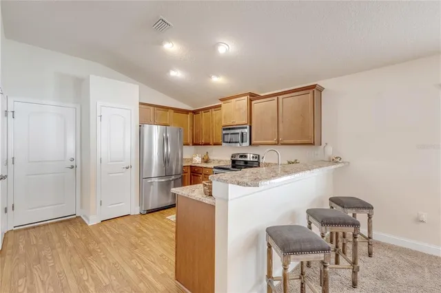 a kitchen with stainless steel appliances granite countertop a sink a stove a refrigerator and island with wooden floor