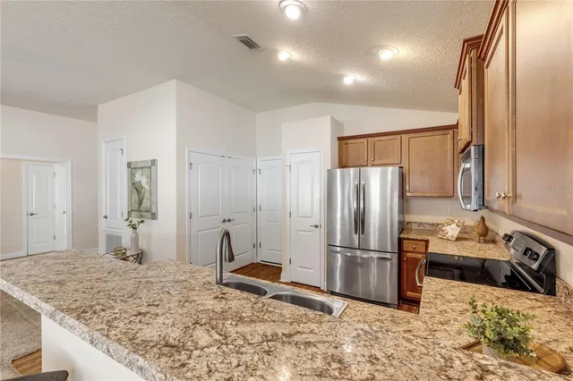 a kitchen with kitchen island granite countertop a refrigerator and a sink