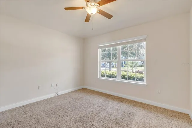 an empty room with a window and a fan