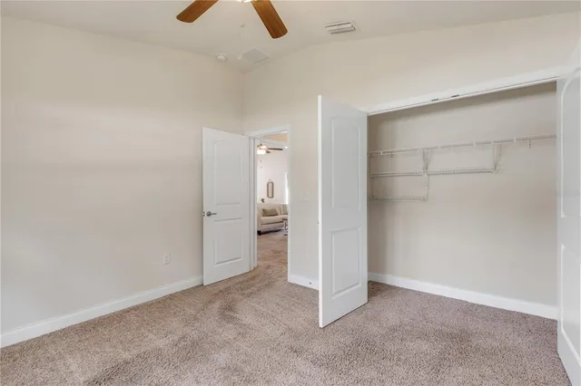 an empty room with ceiling fan and window
