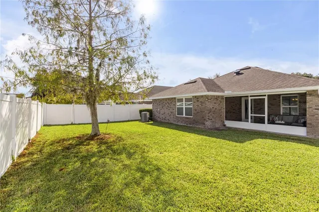 a view of a house with a yard and a large tree