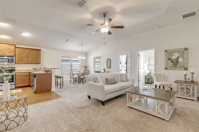 a living room with furniture kitchen view and a chandelier
