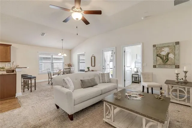 a living room with furniture kitchen view and a chandelier