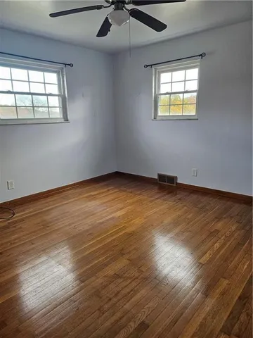 an empty room with wooden floor chandelier and windows