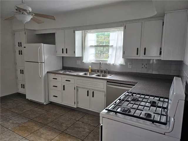 a kitchen with white cabinets and appliances