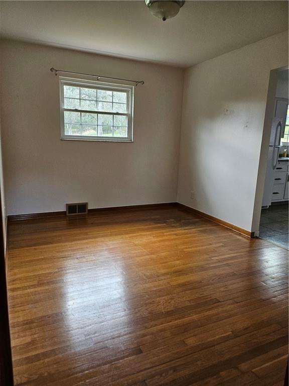 124 Clover Drive Monaca, PA 15061 - Photo 7 of 14 an empty room with wooden floor and windows with curtains
