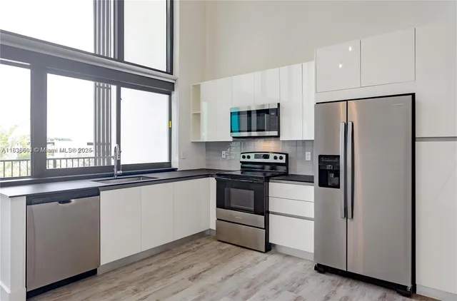 a kitchen with stainless steel appliances granite countertop a refrigerator a stove and a sink with wooden floor