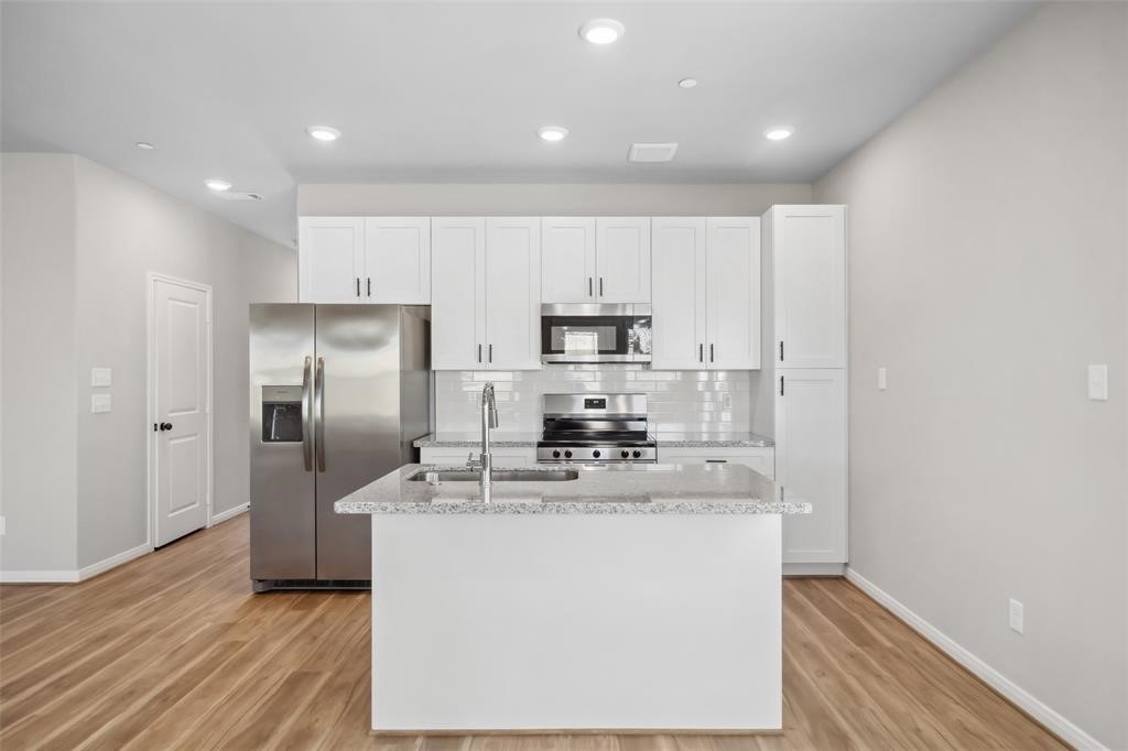 800 North Thompson Street Conroe, TX 77301 - Photo 6 of 25 a kitchen with kitchen island a sink stainless steel appliances and refrigerator