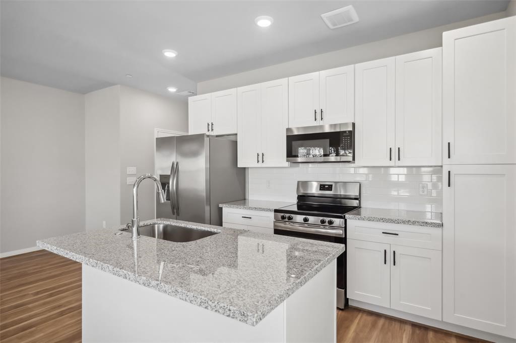 800 North Thompson Street Conroe, TX 77301 - Photo 7 of 25 a kitchen with stainless steel appliances granite countertop a refrigerator a stove and a sink