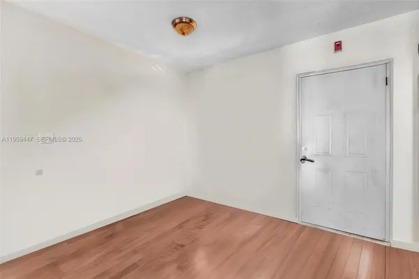an empty room with wooden floor and mirror