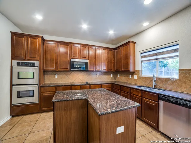 a kitchen with stainless steel appliances granite countertop wooden cabinets a stove and a sink