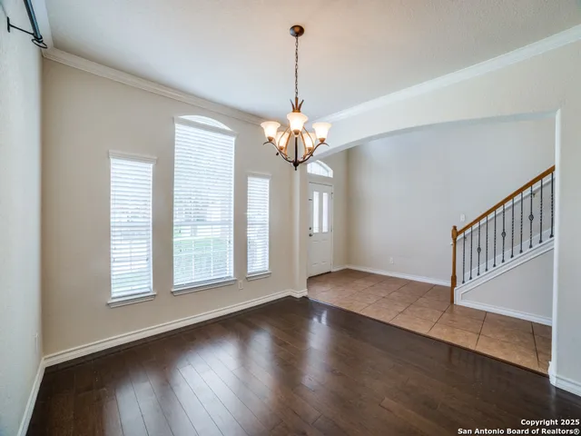 a view of a room with wooden floor chandelier and windows