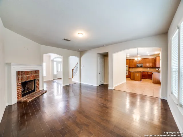 a view of an empty room with wooden floor and a fireplace
