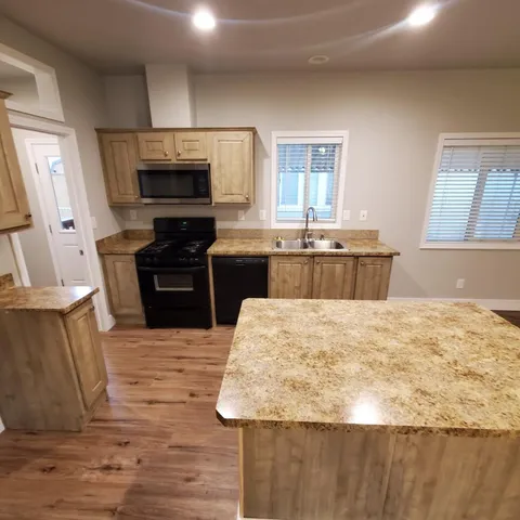 a kitchen with kitchen island granite countertop a stove top oven a sink dishwasher a dining table and chairs with wooden floor