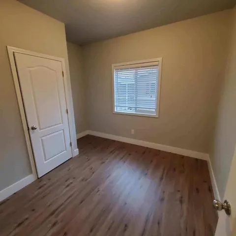 an empty room with wooden floor and window