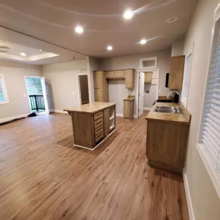 a room with kitchen island stainless steel appliances a sink wooden floor and view living room