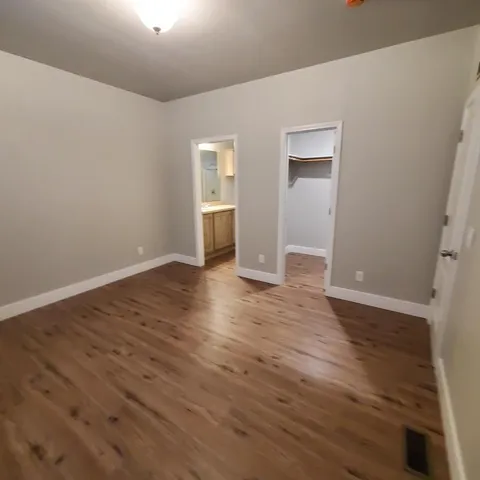 a view of an empty room with wooden floor and closet