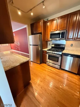 a kitchen with stainless steel appliances granite countertop a refrigerator a stove a sink and a microwave