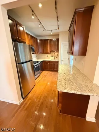 a kitchen with stainless steel appliances granite countertop a refrigerator a stove and a sink