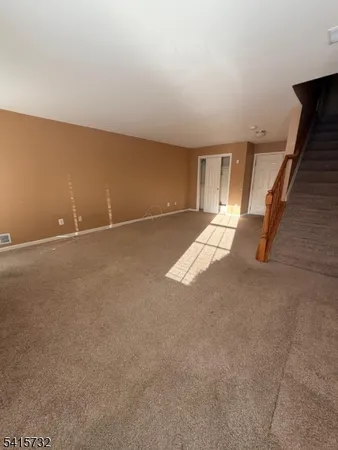 a view of an empty room with stairs and a couch
