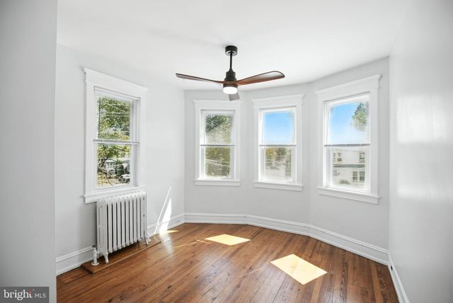 an empty room with wooden floor chandelier fan and windows