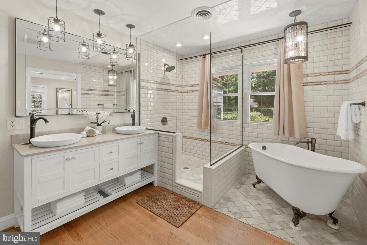 a spacious bathroom with a double vanity sink a mirror and a bathtub