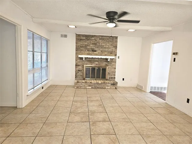 a view of an empty room with a fireplace and a window