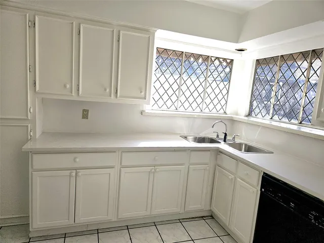 a kitchen with white cabinets and sink