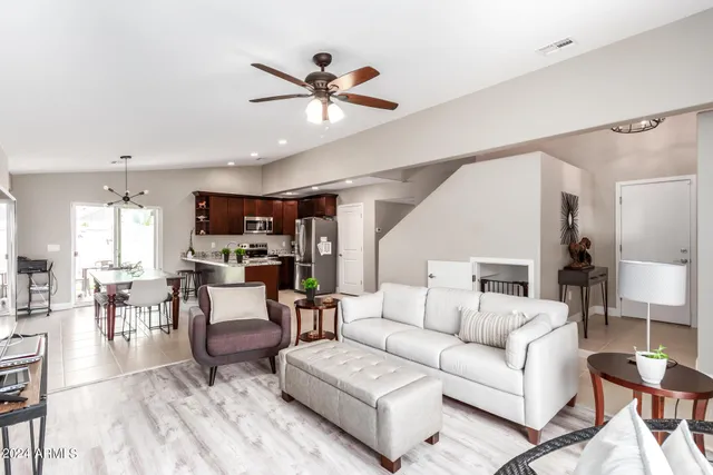 a living room with furniture kitchen view and a wooden floor