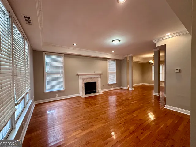 a view of an empty room with wooden floor and a window