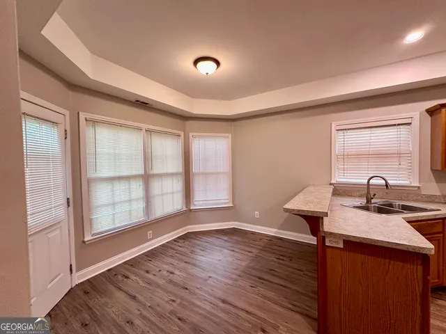 a kitchen with stainless steel appliances granite countertop hardwood floor sink stove and wooden cabinets