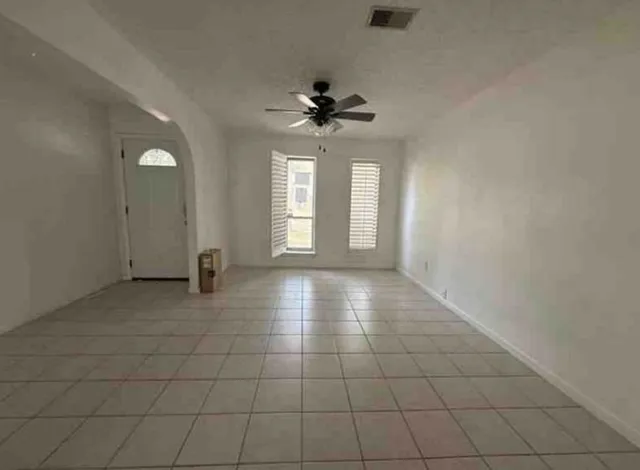 an empty room with windows and ceiling fan